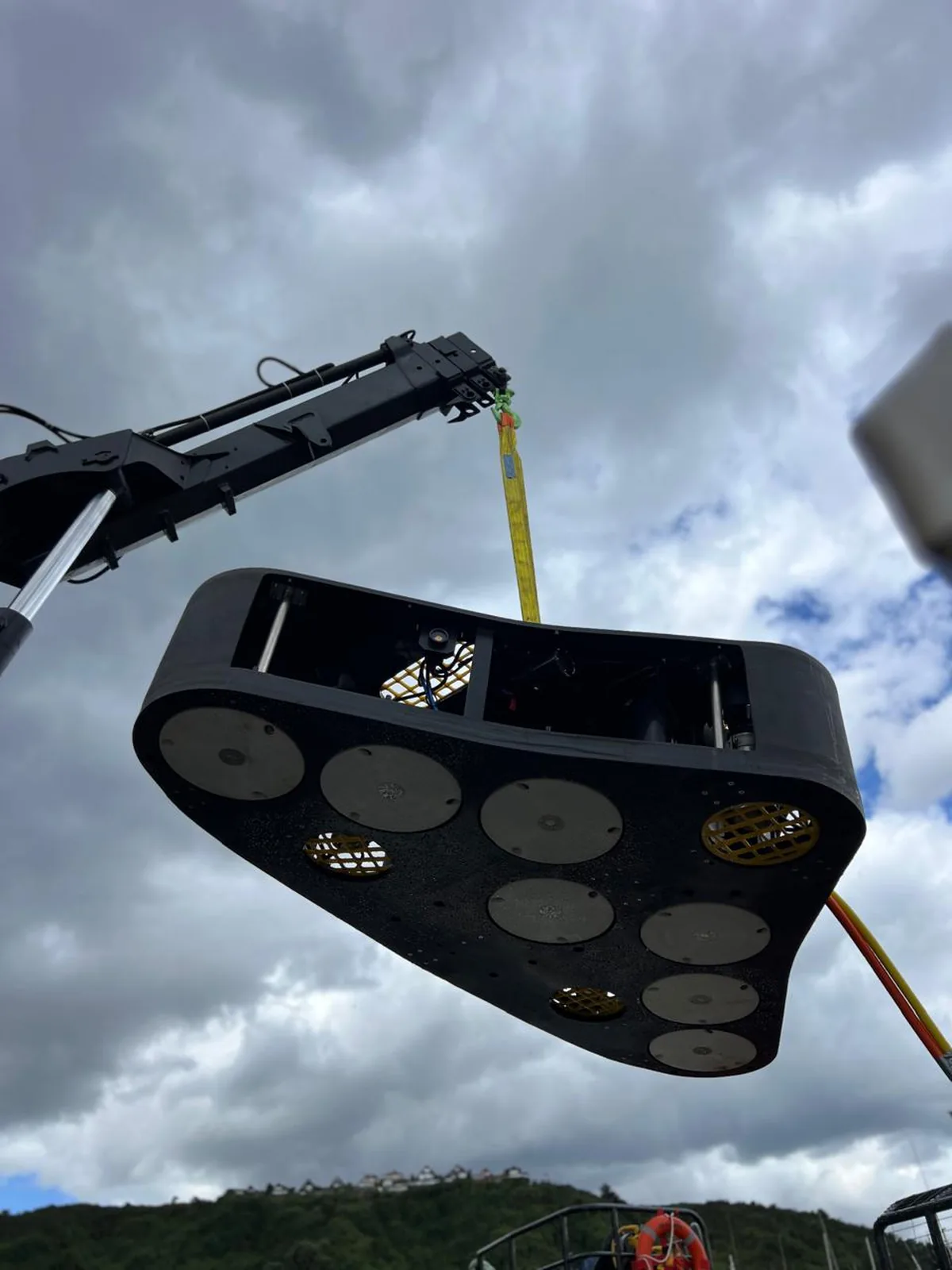 Robot de limpieza de redes de Servimar suspendido de la grúa de cubierta, listo para el despliegue